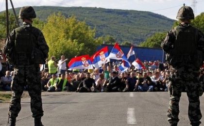 Kosovo Serbs wave flags while sitting on the road in front of Slovenia's KFOR soldiers in the village of Rudare near Zvecan July 29, 2011.