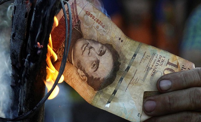 A man burns a 100-bolivar bill during a protest in El Pinal, Venezuela.