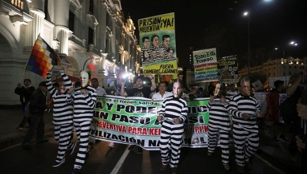 Protesters dressed in mock prison outfits and wearing face masks of Peru's President Pedro Pablo Kuczynski and fellow politicians.