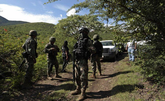 Soldiers guard an area where a mass grave was found, in Colonia las Parotas on the outskirts of Iguala, in Guerrero in October 2014.