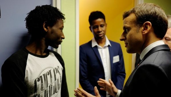 French President Emmanuel Macron (R) talks to Ahmed Adam from Sudan at a migrant center in Croisilles, France, January 16.