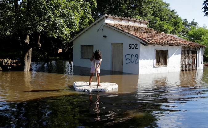 A young girl uses a piece of styrofoam as a paddle board next to a flooded home after heavy rains caused the river Paraguay to overflow, on the outskirts of Asuncion, Paraguay January 23, 2018.