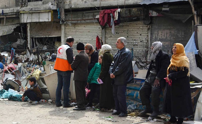 Residents wait to receive humanitarian aid at the Palestinian refugee camp of Yarmuk, in Damascus March 11, 2015