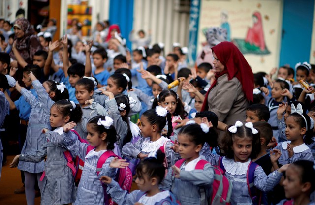 Palestinian schoolchildren participate in the morning exercise at an UNRWA-run school, on the first day of a new school year, in Gaza City.