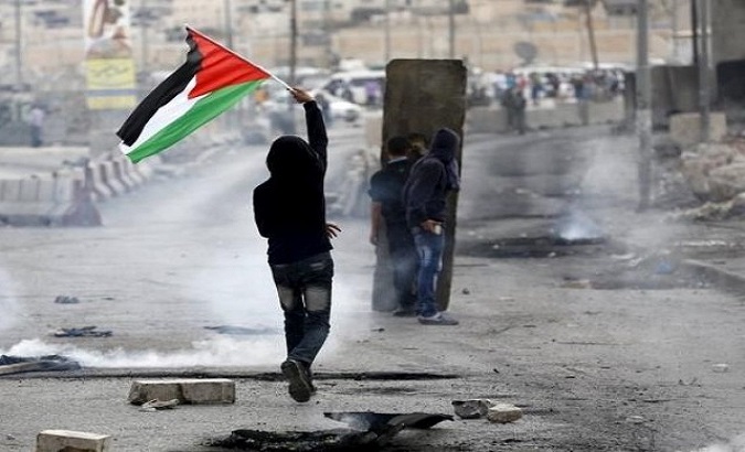 Protester with Palestinian flag during clashes with Israeli army at Qalandia checkpoint near occupied West Bank city of Ramallah, Oct. 6, 2015.