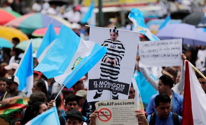 Guatemalans participate in a march against president Morales on Sept. 20. One protester holds and image of Morales dress in a prisoner's uniform.