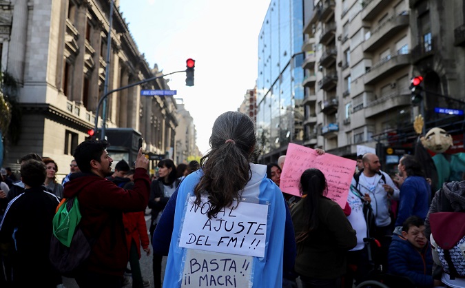 A protester with an Argentine flag reading “No to the IMF adjustment measures - Macri, enough!”  outside the Congress in Buenos Aires, Argentina Oct. 3, 2018