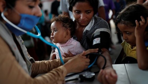 Esmeralda Gonzalez from Honduras receives medical care next to her children, Esmeralda, 11-month-old, and Angel, 5, at a public square in Tapachula, Mexico.