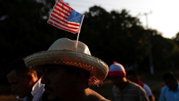 A migrant from Honduras, part of a caravan traveling to the US, wears a hat with the US flag while he walks along the road to Huixtla, near Tapachula, Mexico, October 31, 2018. 