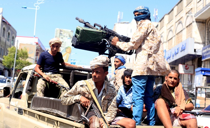 Government soldiers ride on the back of a patrol truck in Taiz.