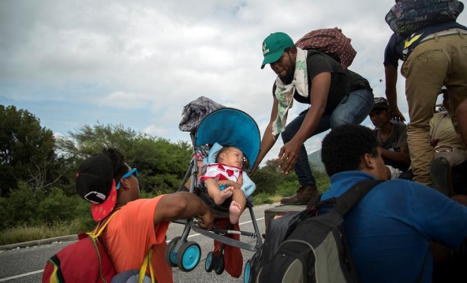 Members of the migrant caravan, or exodus, list a sleeping infant as they pass through Juchitán, Mexico.