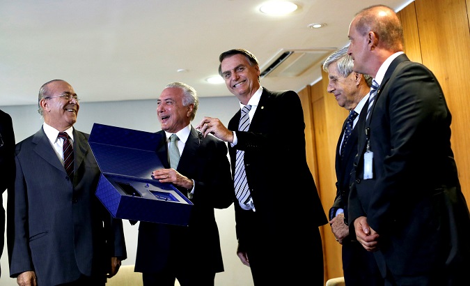 Brazil's President Michel Temer (2nd L) smiles as Brazil's President-elect Jair Bolsonaro (3rd R) holds a key symbolizing the transition of power Nov. 7, 2018.