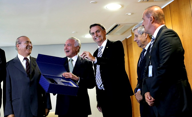 Brazil's President Michel Temer (2nd L) smiles as Brazil's President-elect Jair Bolsonaro (3rd R) holds a key symbolizing the transition between the incoming and outgoing governments.