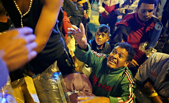 Migrants, part of a caravan of thousands traveling from Central America en route to the U.S., reach for donated blankets at the camp outside La corregidora stadium in Queretaro.