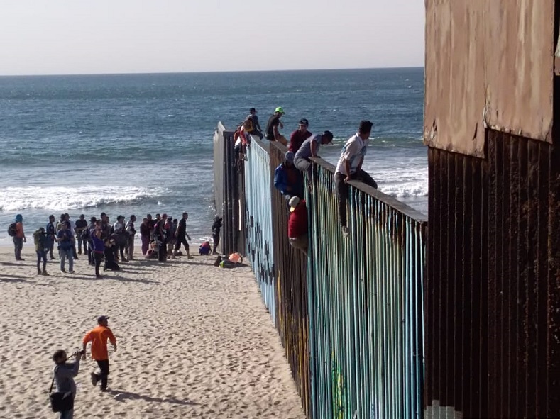 Central American asylum seekers climb the fence at the Tijuana-San Diego border. Many Mexican organizations have helped them as they traveled through the country but the Mexican government has taken measures to deter their U.S. arrival, including blocking 70 buses.