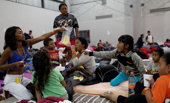Migrants, part of a caravan en route to the United States, eat while they stay in a sports center currently being used as a temporary shelter in Tijuana