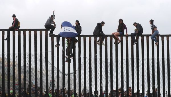 Members of a migrant caravan from Central America and their supporters look through the U.S.-Mexico border wall at Border Field State Park before making an asylum request, in San Diego, California, U.S. April 29, 2018.