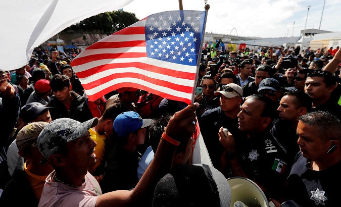 A migrant holds a U.S. flag as the group negotiates with Mexican policemen in Tijuana, Mexico Nov. 22, 2018.