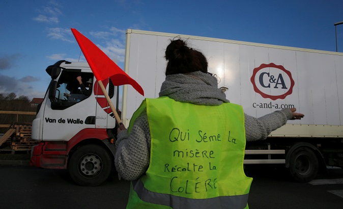 A yellow-vest protester displays a sign that reads 