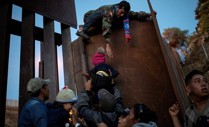 Migrants from Honduras, part of a caravan of thousands from Central America trying to reach the United States, try to jump a border fence to cross illegally from Mexico to the U.S, in Tijuana.