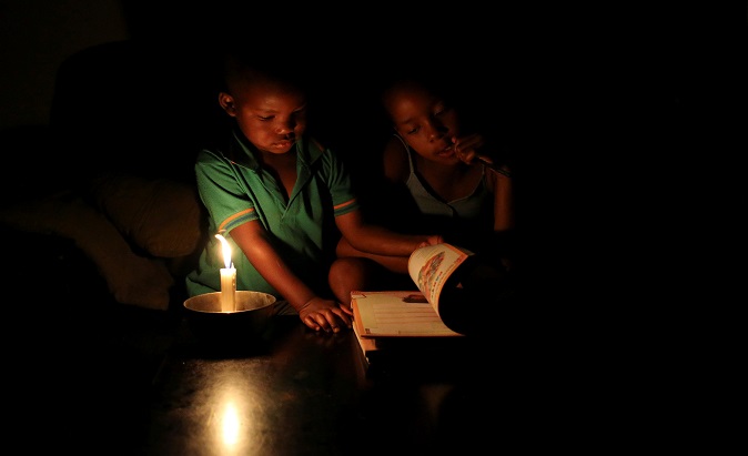 Sinovuyo Bhungane and her cousin Yonga study by candle light during load shedding in Soweto, South Africa, Feb. 3, 2015.