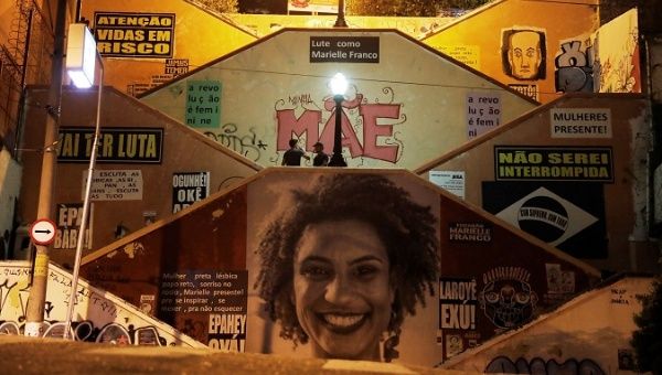 Men talk next to an image in tribute to late human rights activist and council woman Marielle Franco - who was assassinated in a shooting - nine months after her death, on Human Rights Day in Sao Paulo, Brazil, December 10, 2018.