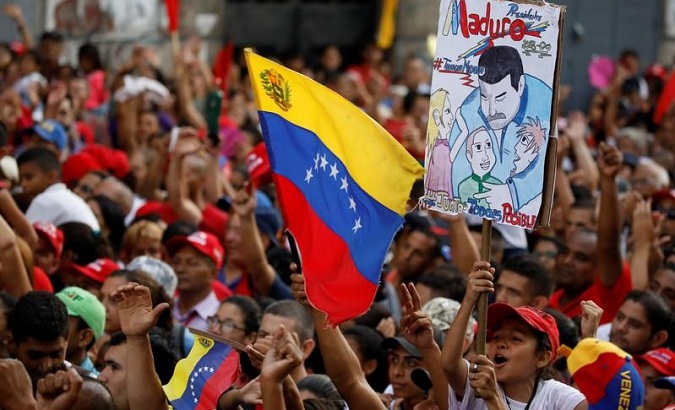 Supporters of Venezuela's President Nicolas Maduro carrying a placard depicting him and waving a Venezuelan flag attend to a campaign rally in Caracas, Venezuela May 4, 2018.