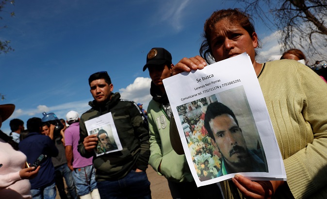 Residents hold pictures of their missing relative at the site where a fuel pipeline ruptured by suspected oil thieves exploded, in the municipality of Tlahuelilpan, state of Hidalgo, Mexico January 19, 2019.