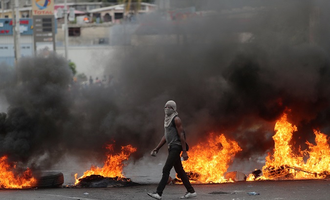 A demonstrator walks past a burning barricade during anti-government protests in Port-au-Prince, Haiti, February 15, 2019.