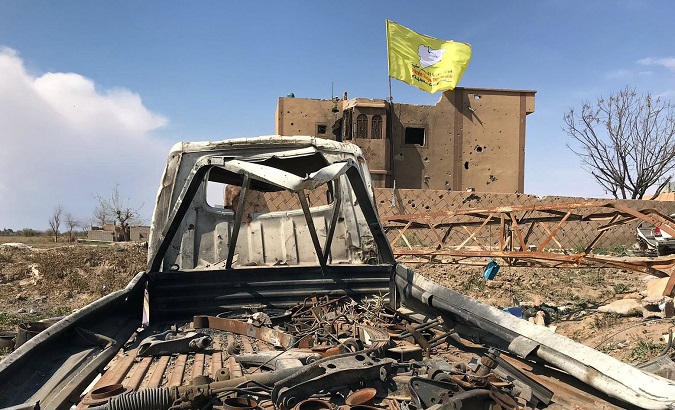 Syrian Democratic forces flag flutters on a damaged building in the village of Baghouz, Deir Al Zor province
