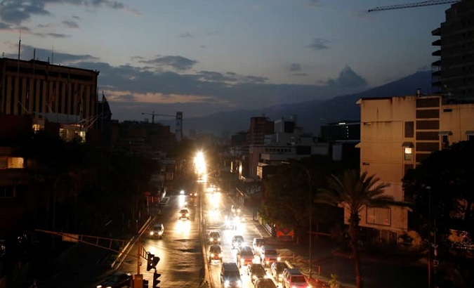 Traffic lights up darkened buildings in Caracas on during a blackout.