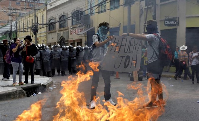 Protesters hold an anti-government sign in front of a group of police during a protest Tuesday in Tegucigalpa.