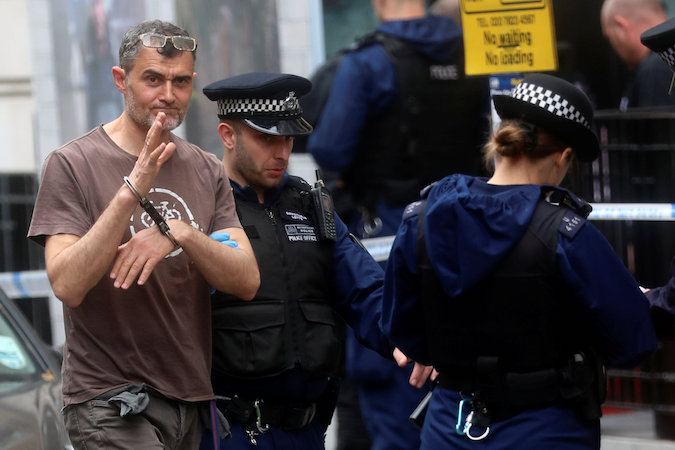 A Greenpeace activist waves while being detained by police after blocking the entrance to BP headquarters in London, Britain May 20, 2019.
