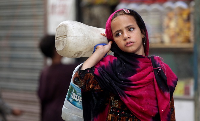 A girl from an Afghan refugee family carries bottles to be filled from a nearby tap in a low-income neighborhood in Lahore, Pakistan June 20, 2019.