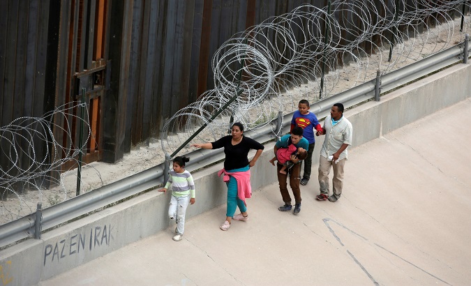 Migrants walk along the border fence at Ciudad Juarez, Mexico July 17, 2019.