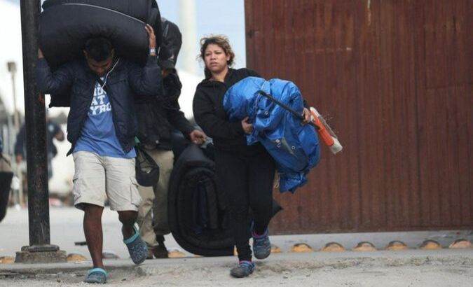 Asylum-seekers, part of a caravan of thousands from Central America tying to reach the United States, carry their belongings during the closing of the Barretal shelter in Tijuana.