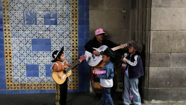 A woman and her children play guitars as they wait for pedestrians to donate coins along a sidewalk near Zocalo Square in Mexico City August 7, 2014. (Photo: Reuters)