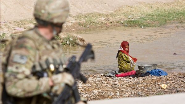 Afghan girl washing clothes in a river looks at a U.S. Army soldier in the town of Senjaray, Zahri district of Kandahar province. May 29, 2012. (Photo: Reuters)