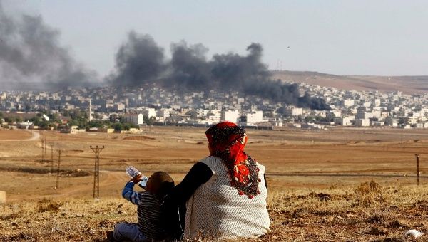 Turkish Kurds watch smoke rises over Syrian town of Kobani after an airstrike, as seen from the Mursitpinar border crossing on the Turkish-Syrian border in the southeastern town of Suruc in Sanliurfa province, October 18, 2014 (Reuters)