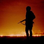 A U.S. soldier stands night guard as oil wells burn in the distance in Kuwait, just south of the Iraqi border Feb. 26, 1991.