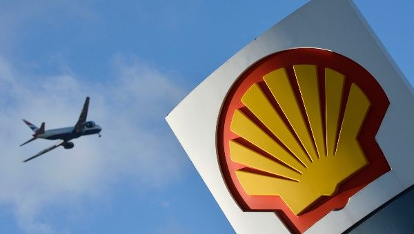 A passenger plane flies over a Shell logo at a petrol station in west London, January 29, 2015