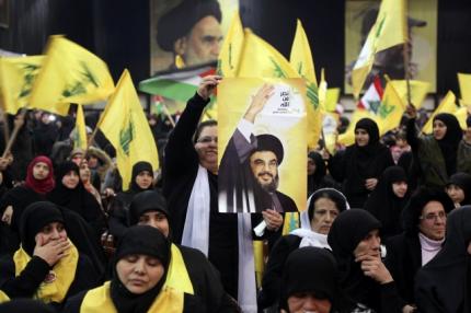 A supporter of Lebanon's Hezbollah leader Sayyed Hassan Nasrallah holds up a poster of him
