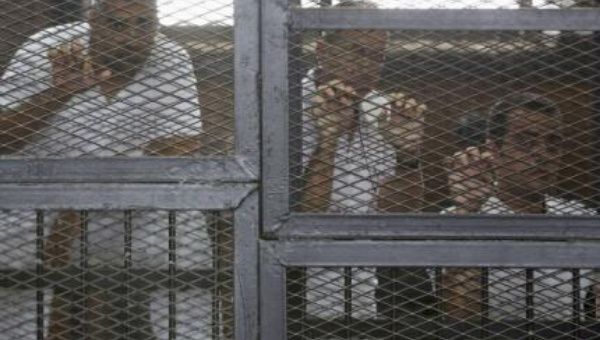 Al Jazeera journalists (L-R) Mohamed Fahmy, Peter Greste and Baher Mohamed stand behind bars at a court in Cairo.