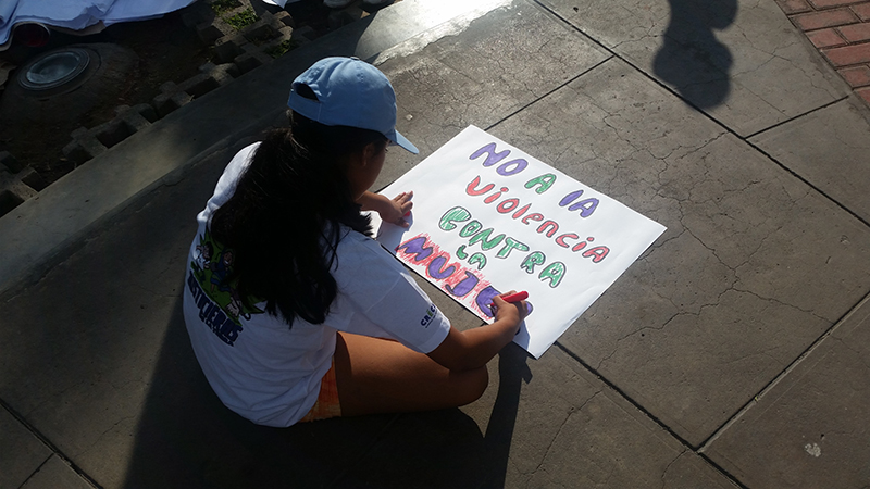 Child prepares sign for the International Women's Day March in Peru.