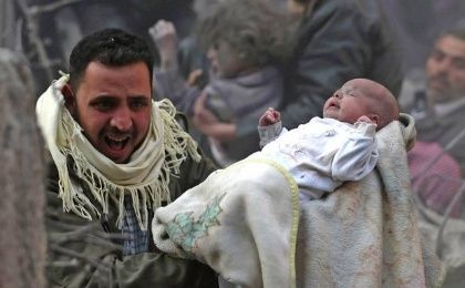 A man tries runs carrying a baby as war-torn Syria enters its fifth year of conflict.