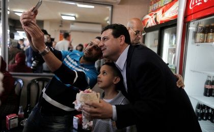 Ayman Odeh (R), head of the Joint Arab List, poses for a photograph together with people at a restaurant during a campaign stop in the northern Israeli city of Acre March 13, 2015. 