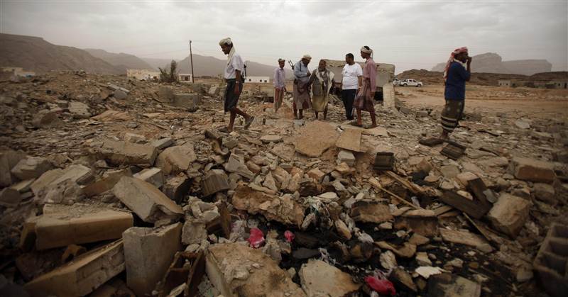 Tribesmen in Azan, Yemen stand on the rubel of a building destroyed by U.S. drone attacks.