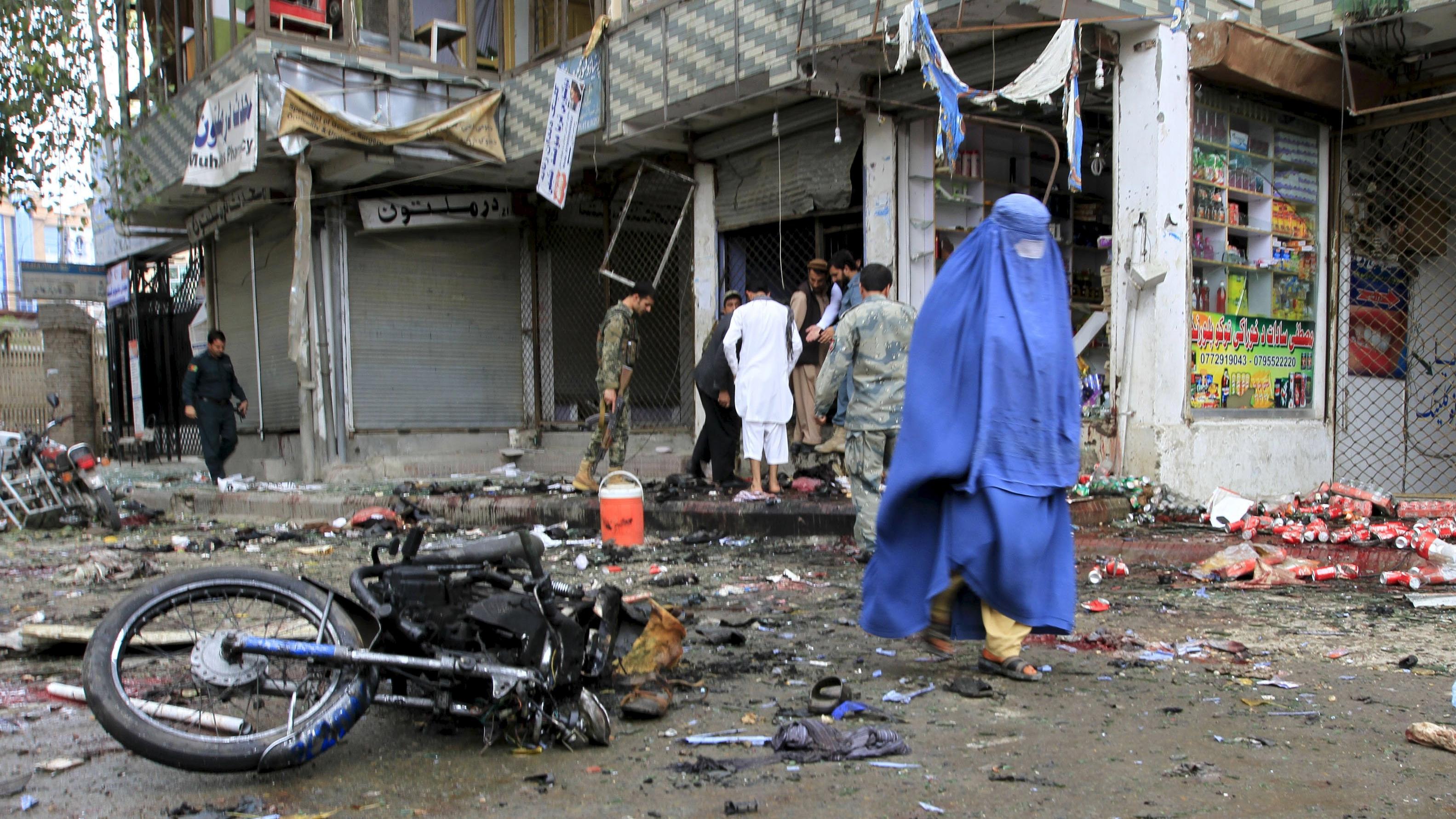 An Afghan woman walks at the site of a suicide attack in Jalalabad April 18, 2015. The suicide bomb blast in Afghanistan's eastern city of Jalalabad occurred outside a bank where government workers collect salaries, the city's police chief said on Saturday.