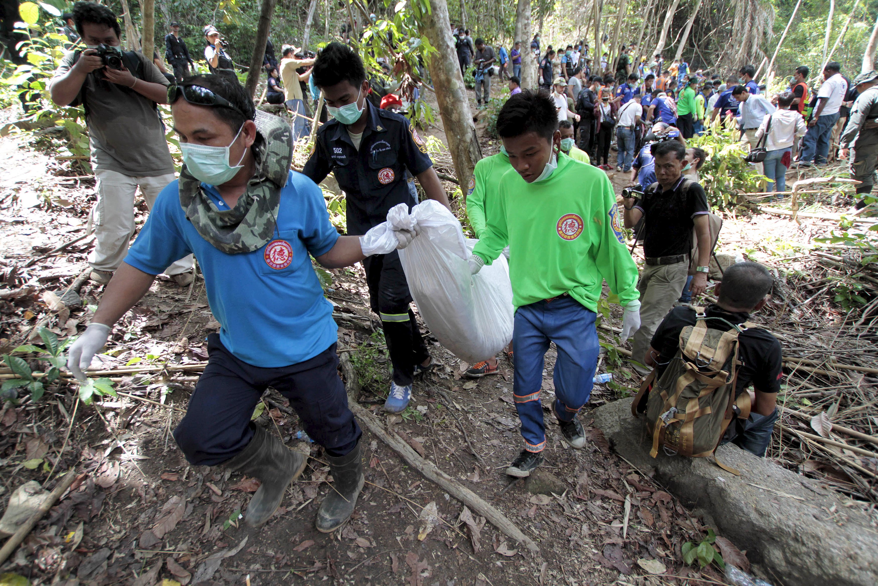 Rescue workers carry a body bag with remains retrieved from a mass grave at an abandoned camp in a jungle some three hundred meters from the border with Malaysia, in Thailand's southern Songkhla province.