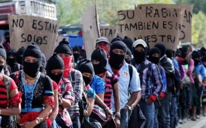 Members of the EZLN hold banners saying Members of the EZLN hold banners saying 